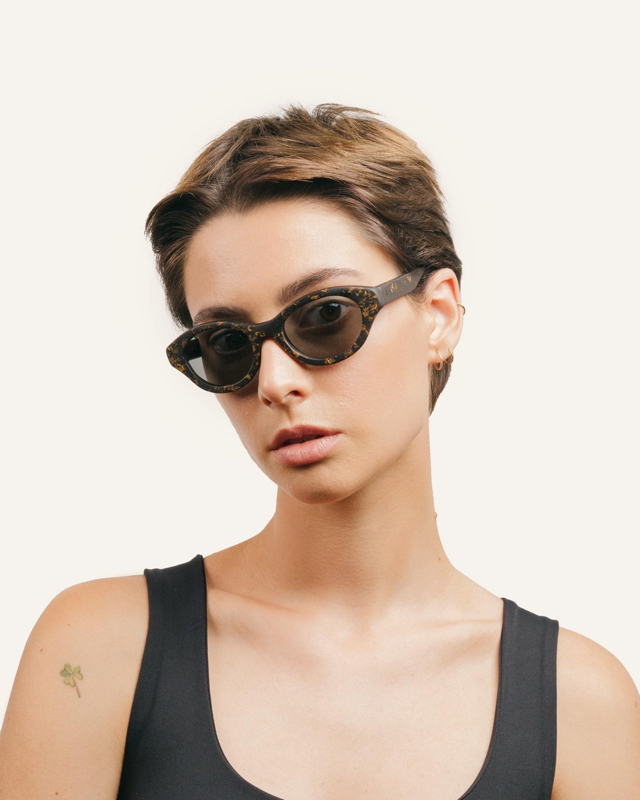 Laden Sie das Bild in den Galerie-Viewer, Woman wearing eco-friendly sunglasses with sunflower petal details and sleek gray lenses for sustainable fashion