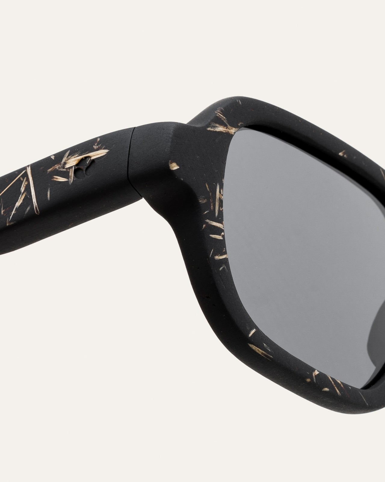 Laden Sie das Bild in den Galerie-Viewer, Close-up of black sunglasses with flax details and gray lenses, highlighting sustainable craftsmanship.