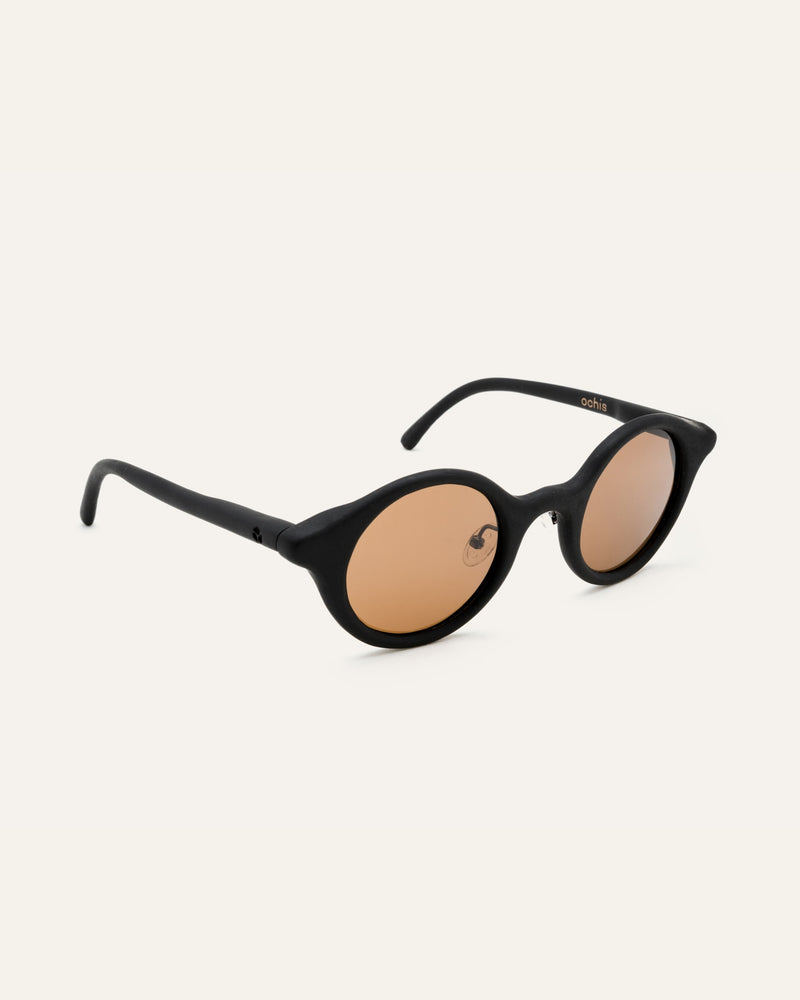 Round black sunglasses with warm brown lenses, crafted from sustainable coffee-based materials for eco-conscious style.