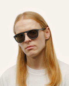 Man with long hair in sustainable sunglasses, highlighting lightweight construction and natural materials.