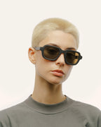 Woman wearing sunglasses with brown lenses, bold, sustainable design.