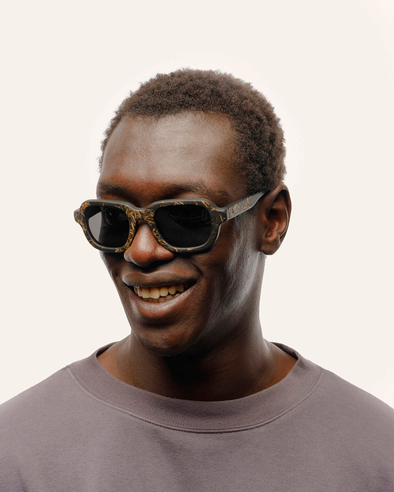 Load image into Gallery viewer, Man wearing eco-friendly sunglasses with gray lenses and a textured black frame.
