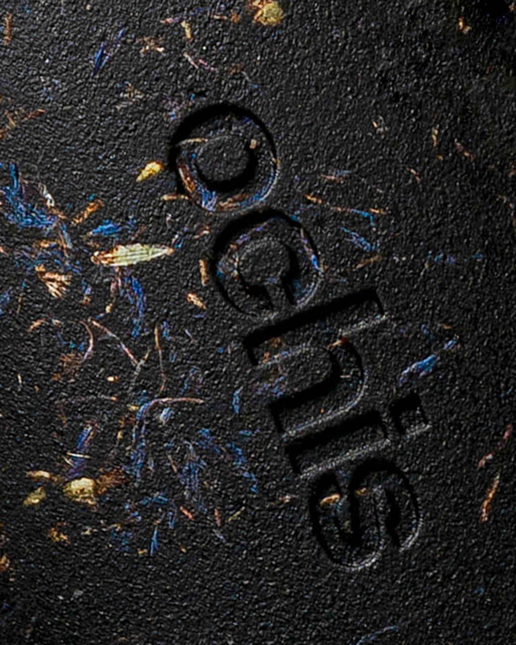 Close-up of the Ochis logo on a coffee-based case, enhanced with natural cornflower petals for a distinctive look
