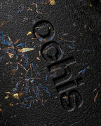 Close-up of the Ochis logo on a coffee-based case, enhanced with natural cornflower petals for a distinctive look