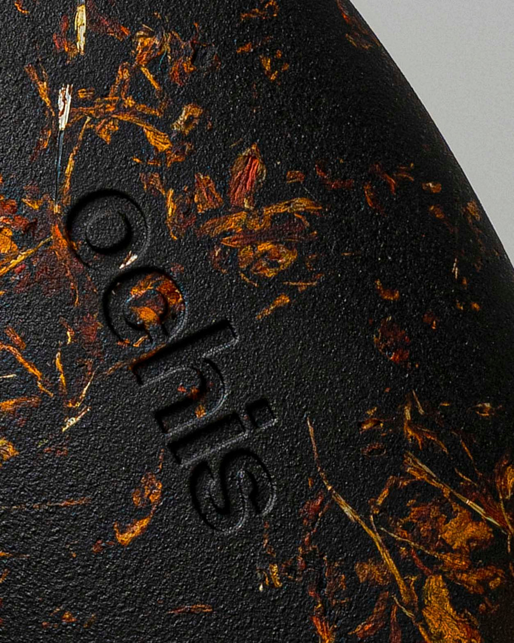 Close-up of the Ochis logo on a coffee-based case enriched with marigold petals, emphasizing handcrafted sustainability