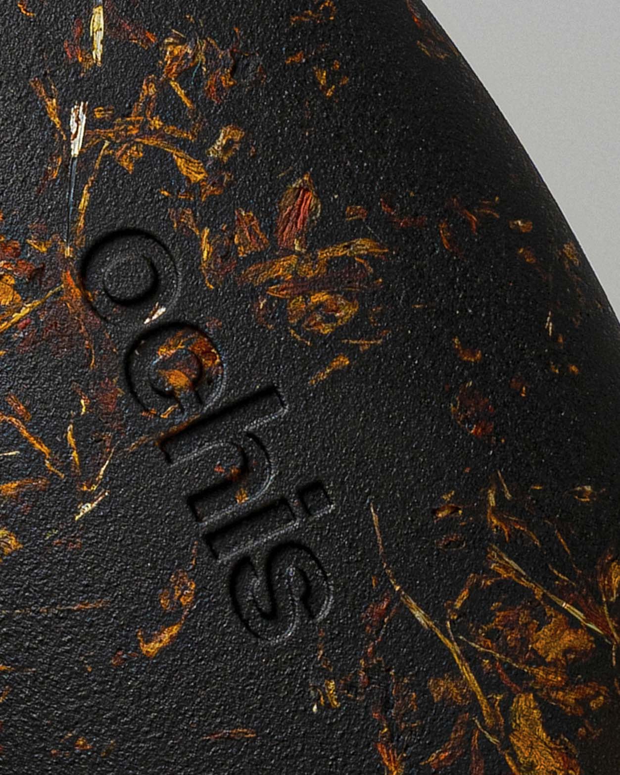 Close-up of the Ochis logo on a coffee-based case enriched with marigold petals, emphasizing handcrafted sustainability