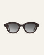 Round dark brown speckled sunglasses with gray gradient lenses on a beige background.
