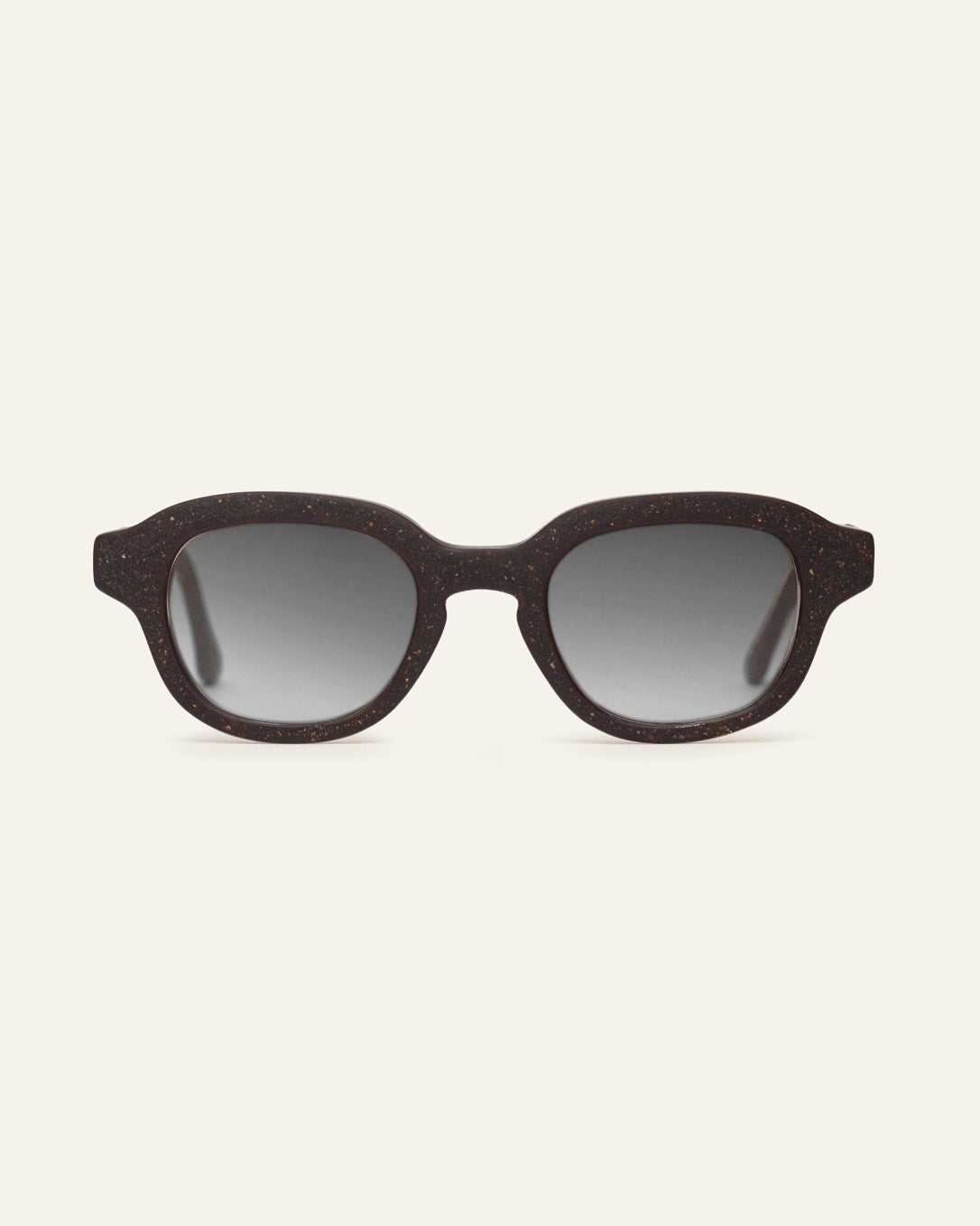 Round dark brown speckled sunglasses with gray gradient lenses on a beige background.