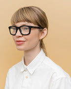 Woman wearing Dandy eco-optical frames, showcasing their black finish and flax-covered temple accents for a sustainable touch