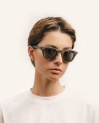 Woman wearing bold eco-friendly sunglasses, showcasing sunflower-inspired details and sleek gray lenses