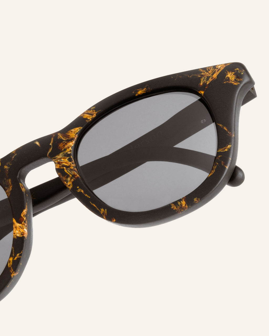 Close-up of lightweight sunglasses, featuring artistic sunflower petal textures on a coffee-based frame.