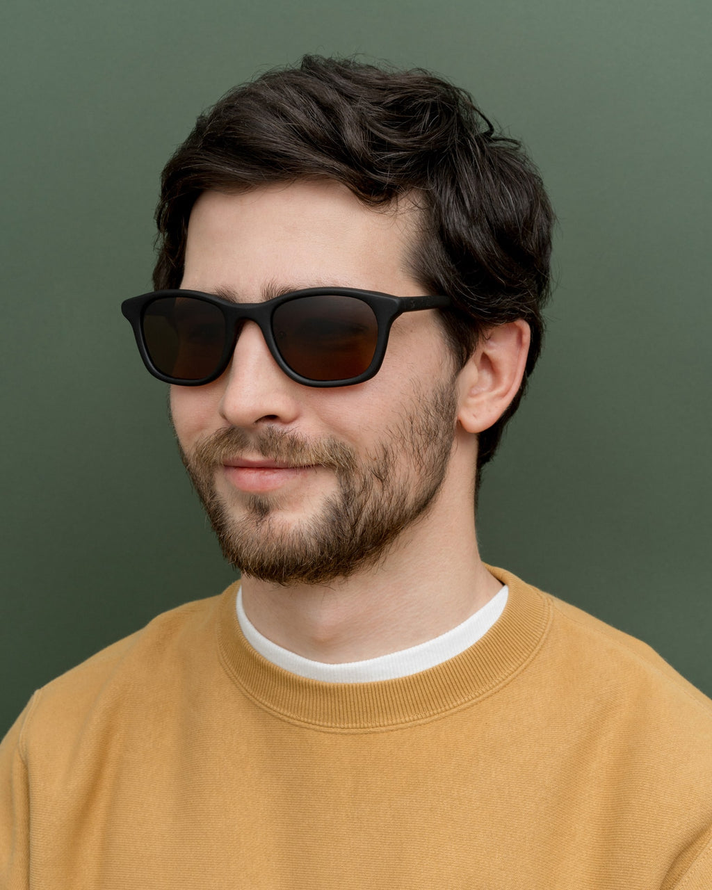 Man in modern black sunglasses with warm-toned lenses, highlighting their minimalist and eco-friendly design.
