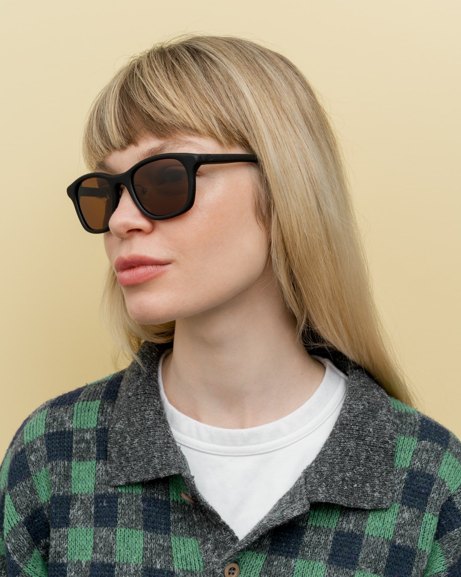 Blonde woman wearing lightweight black sunglasses with brown lenses, perfect for sustainable fashion lovers.