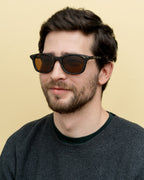 Man wearing sustainable black sunglasses with warm brown lenses, perfect for daily use in California.
