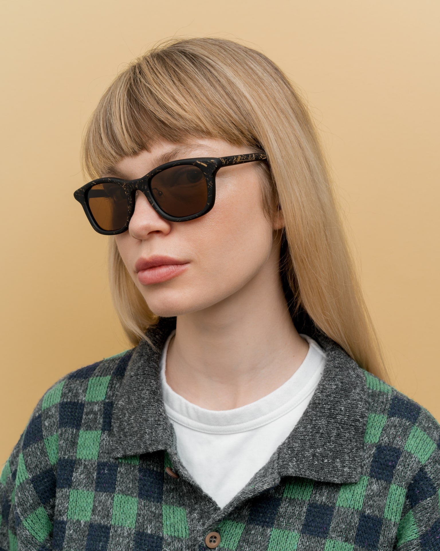 Blonde woman wearing minimalist black sunglasses with natural flax accents, ideal for eco-conscious travelers in Scandinavia.
