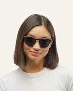 Woman wearing Anderson Black sunglasses with brown lenses, showcasing their stylish and sustainable look.