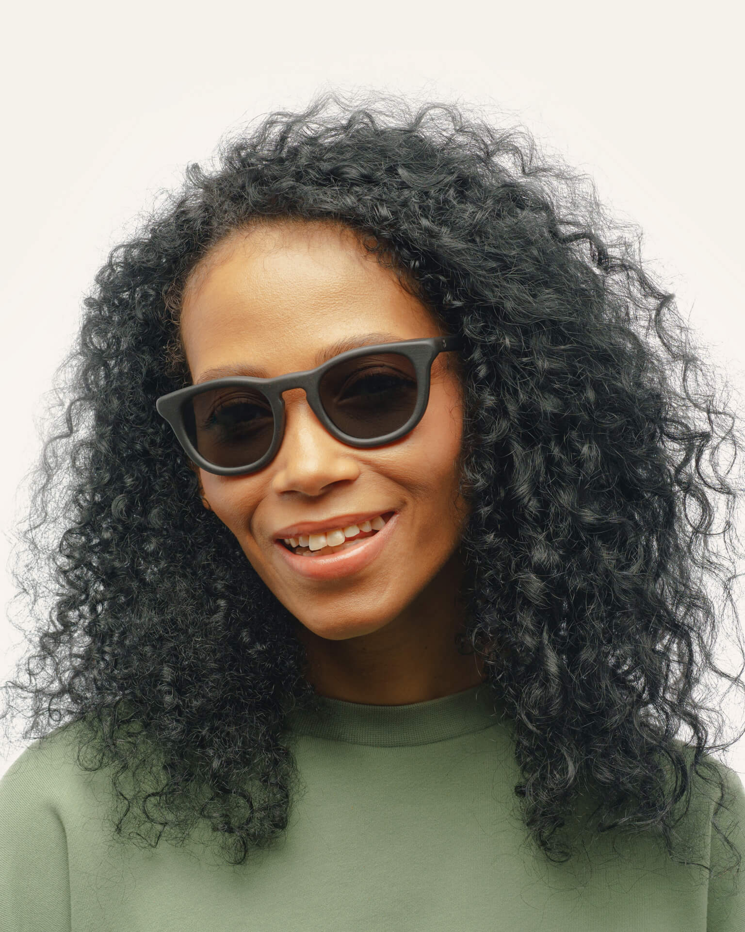 Woman with curly hair wearing Anderson Black sunglasses with brown lenses, highlighting their unisex appeal and timeless style.
