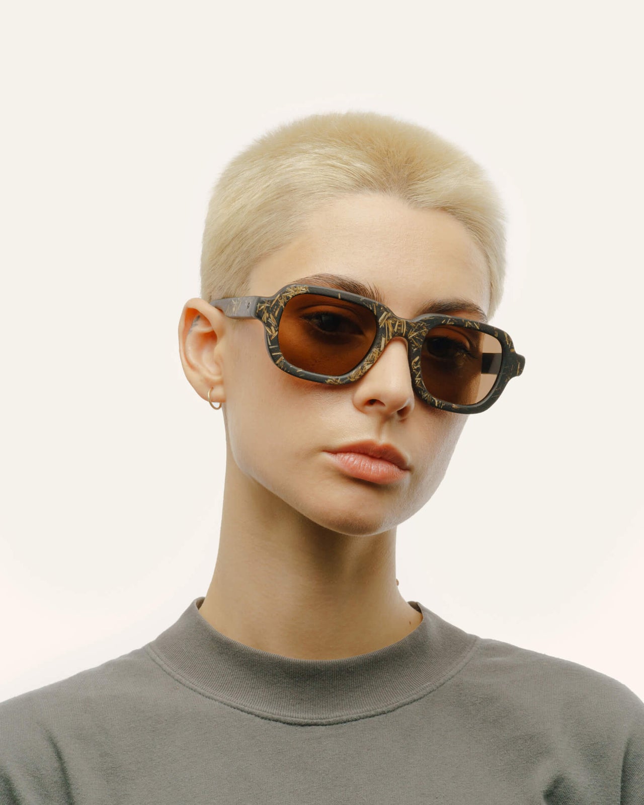 Load image into Gallery viewer, Woman styling sunglasses with brown lenses, showcasing a modern and sustainable textured design.
