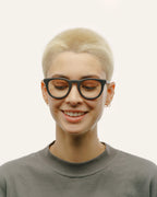 Woman smiling while wearing Anderson Black optical frames, showcasing their sleek design and coffee-based material