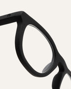 Close-up of trapezoidal prescription optical frames, showing their smooth black finish and eco-friendly coffee-based design.