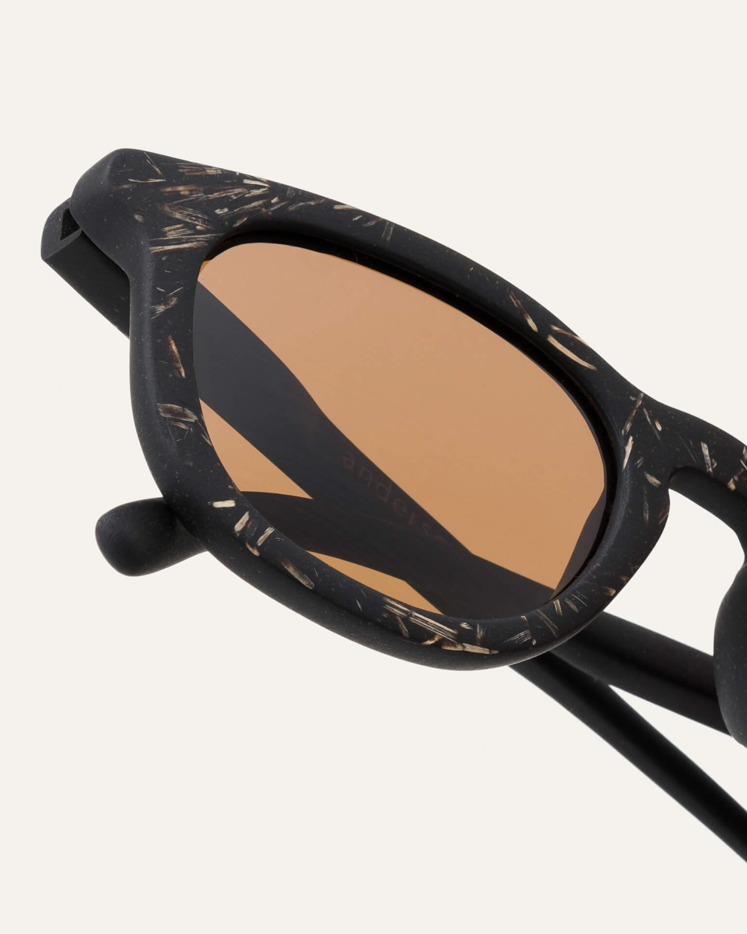  Close-up of sustainable sunglasses, featuring textured flax-covered frames and brown lenses.
