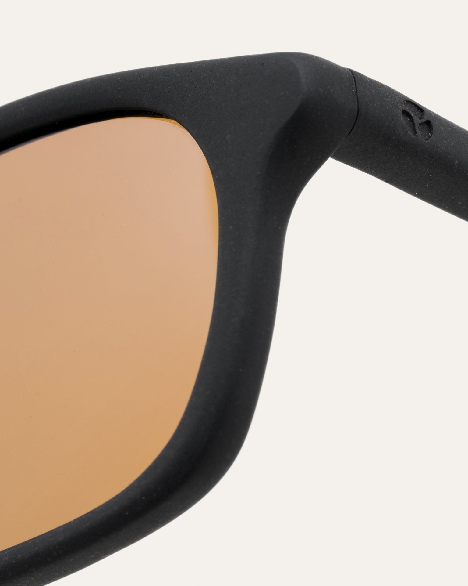 Close-up of warm brown lenses in black sunglasses, emphasizing their handcrafted eco-conscious frame.