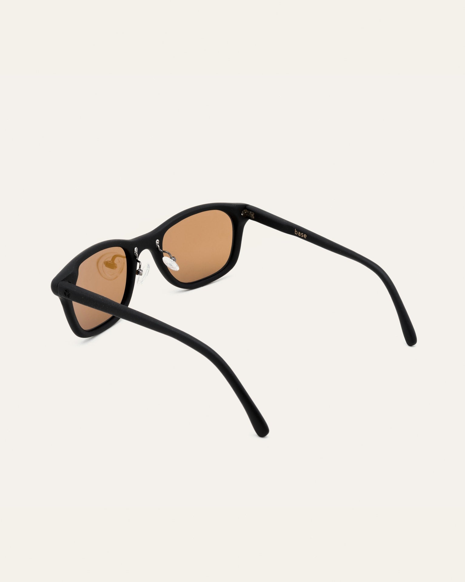 Detailed view of black sunglasses with brown lenses, highlighting their polished finish and sustainable materials.