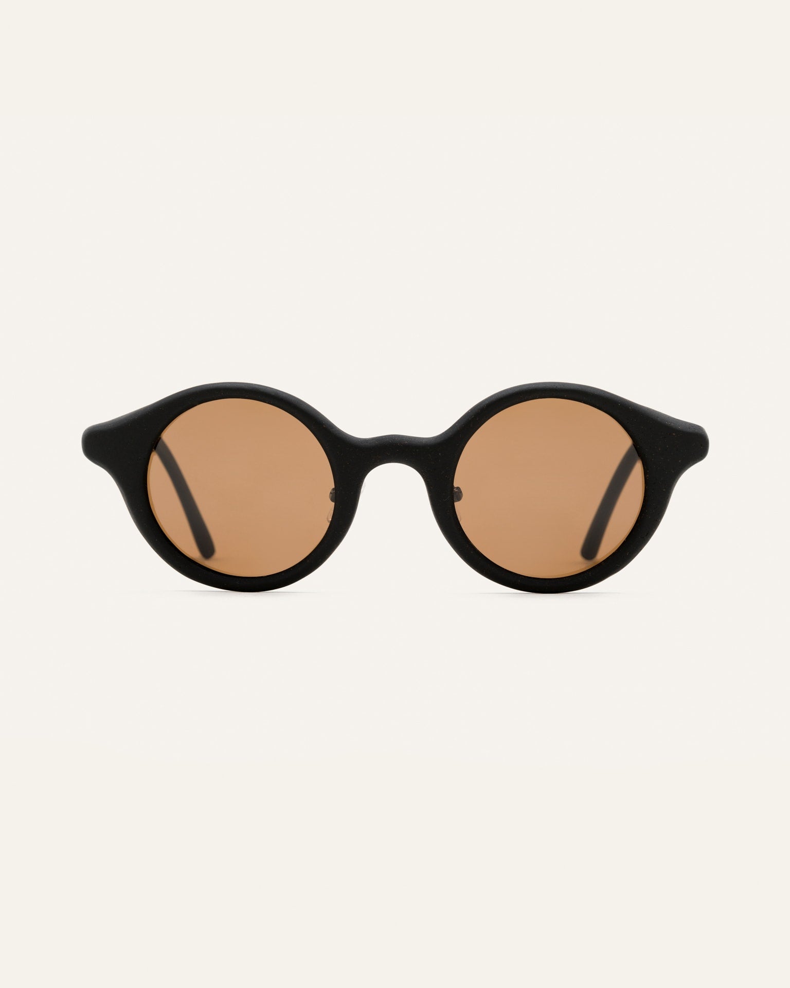 Round black sunglasses with warm brown lenses, crafted from sustainable coffee-based materials for eco-conscious style.