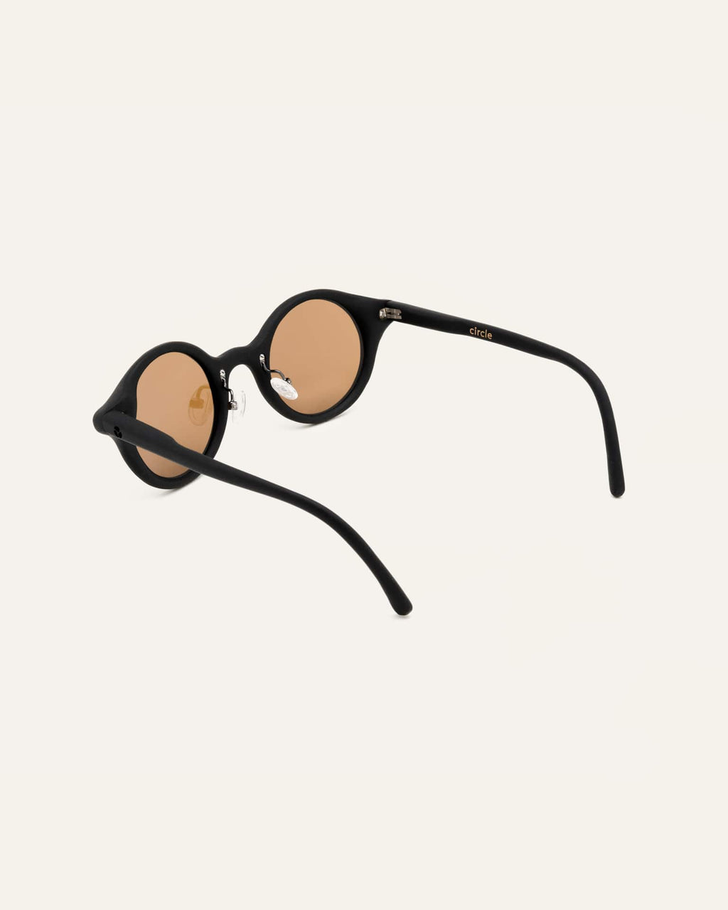 Angled view of black round sunglasses with warm lenses, showcasing their lightweight construction and natural materials.