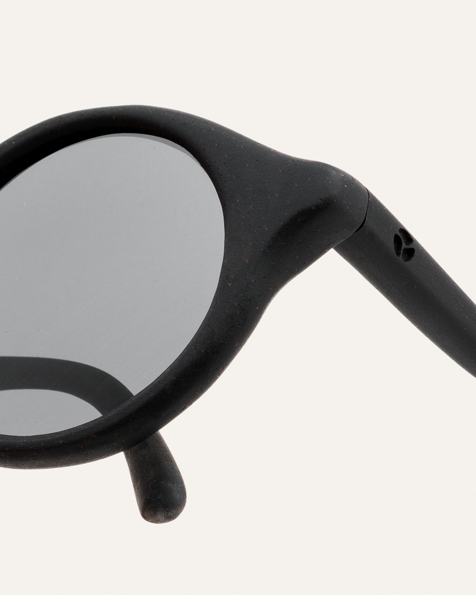 Close-up of gray lenses in round black sunglasses, showing the smooth frame finish and attention to detail.