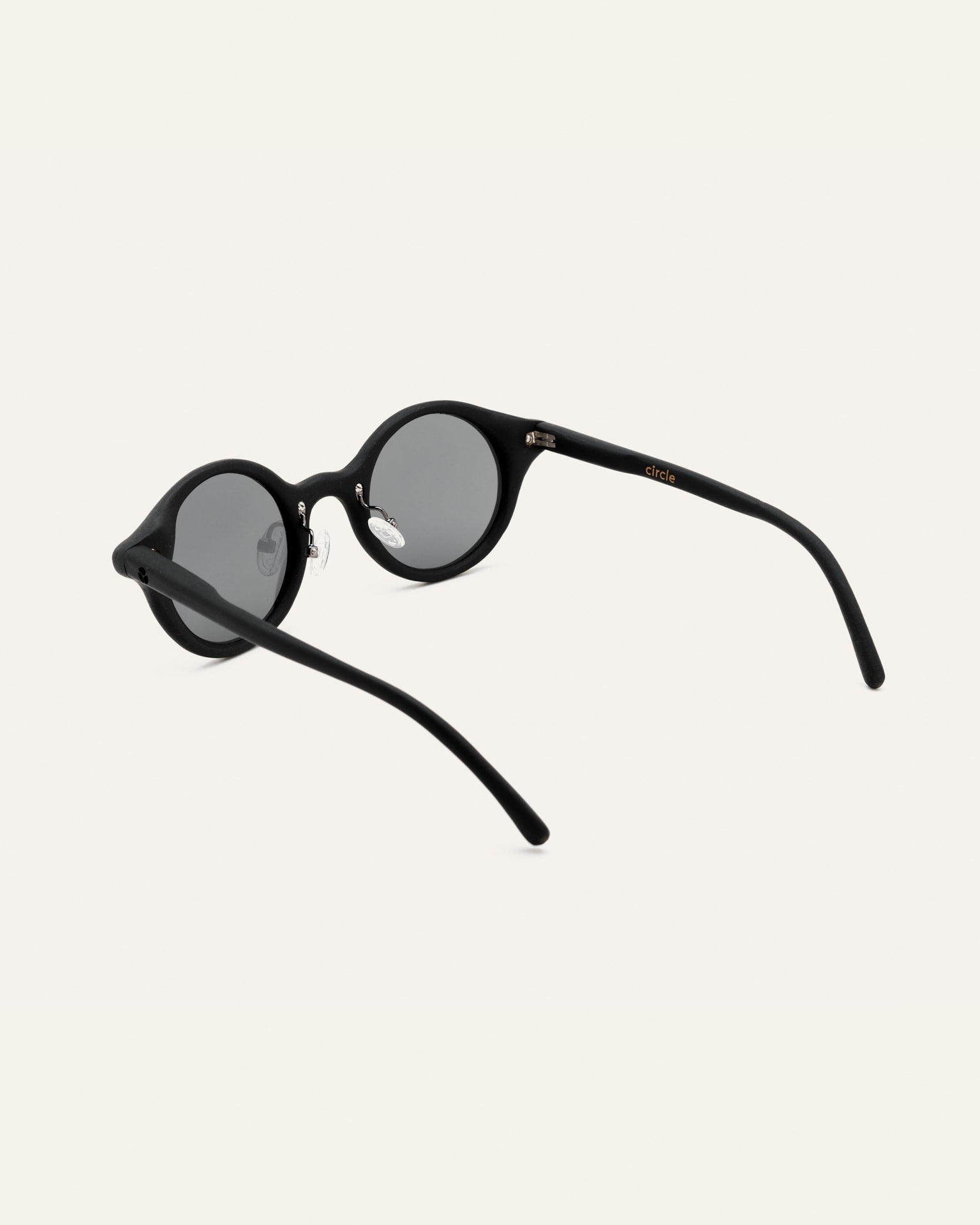 Angled view of lightweight round sunglasses with gray lenses, highlighting their simple and durable design.