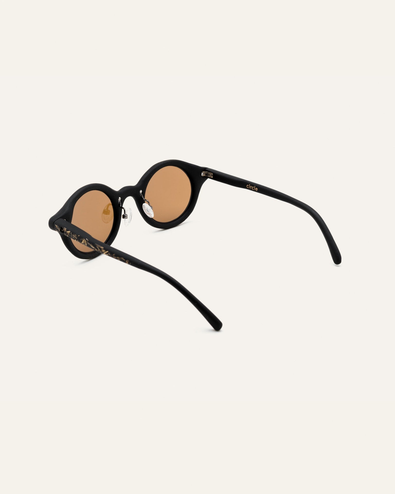 Angled view of sunglasses with flax-enhanced black frames and warm brown lenses, designed for sustainable fashion lovers