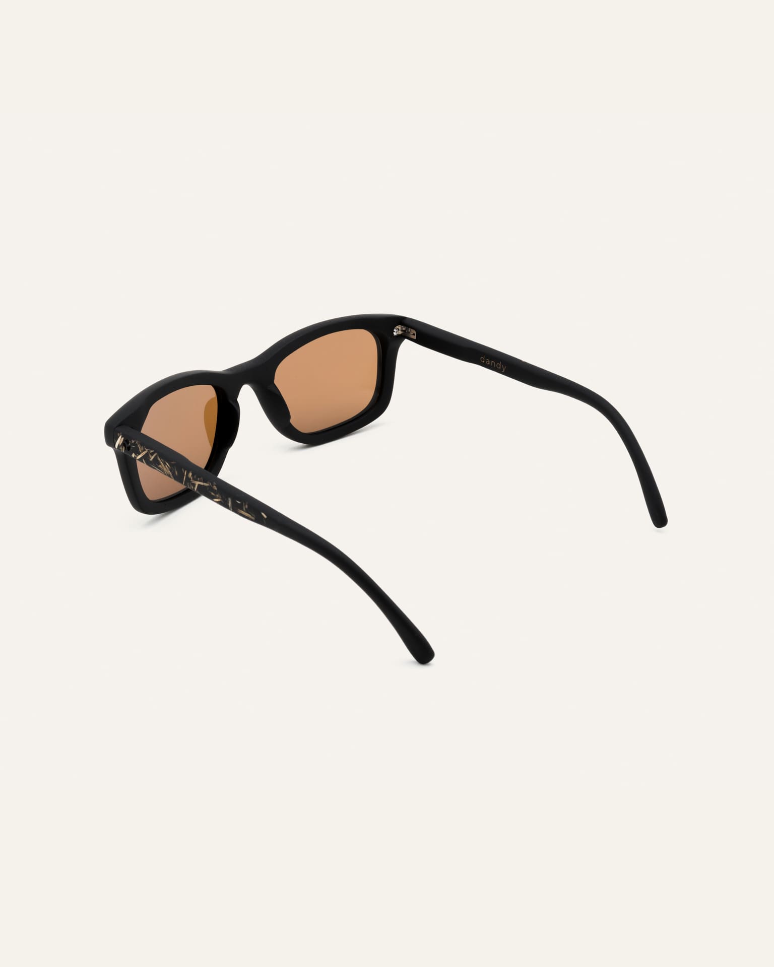 Angled view of Dandy sunglasses with earthy-toned lenses, emphasizing their minimalist and sustainable design.