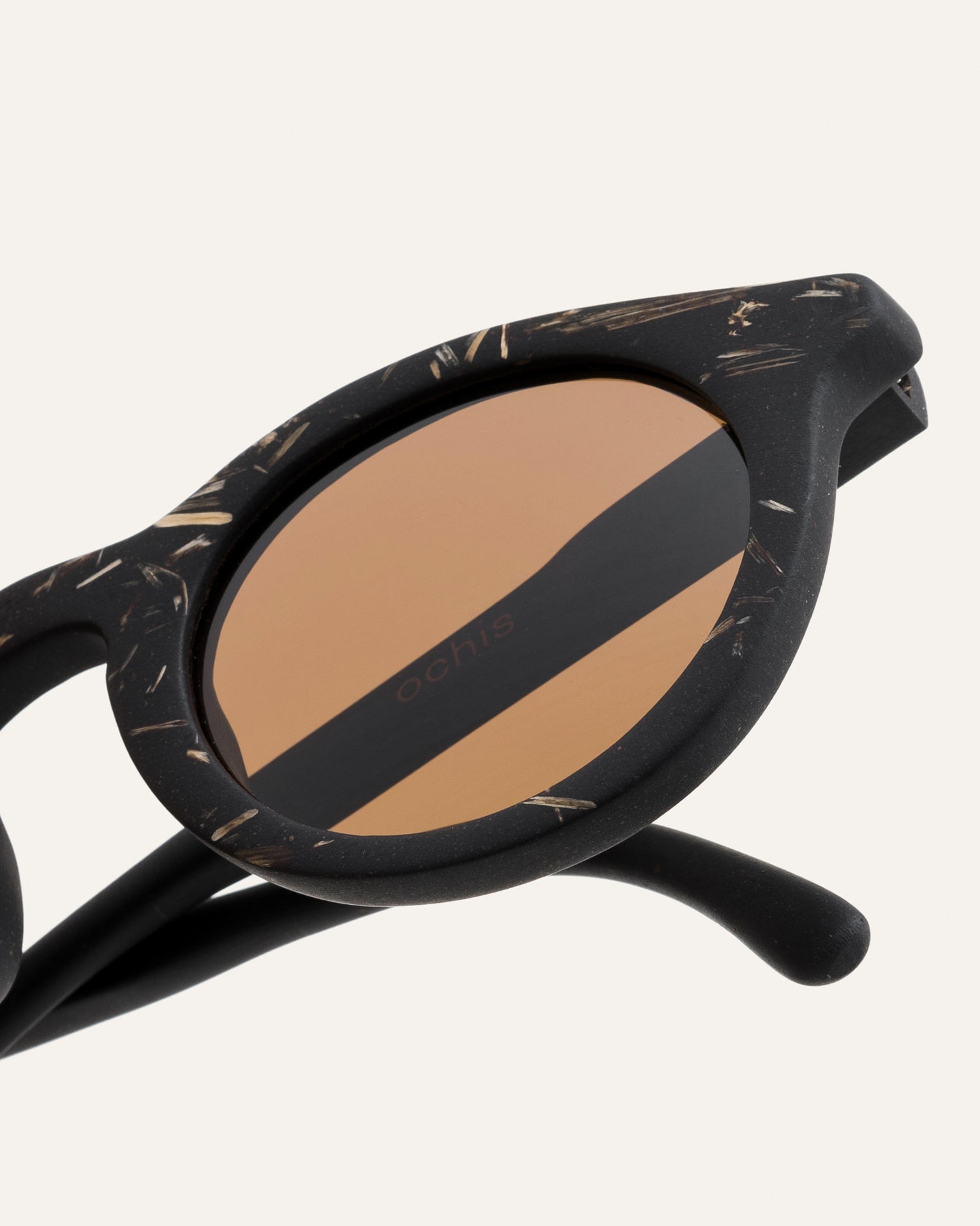 Close-up of black sunglasses showcasing the intricate flax straw texture on sustainable coffee-based frames