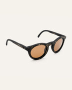 Angled view of black sunglasses with brown lenses, highlighting the natural flax accents on the handcrafted frames